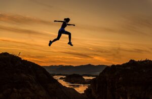 Woman jumping high over chasm