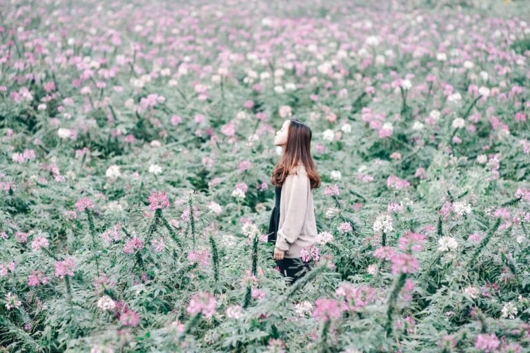 Girl, standing among flowering plants