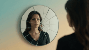 Woman looking at cracked mirror reflection representing imposter syndrome recovery journey